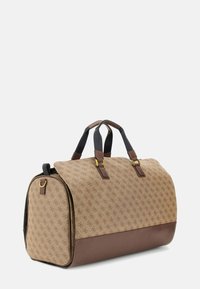 Sac de voyage avec un corps en tissu à motif beige et des accents en cuir marron. Dispose de deux poignées robustes et de quincaillerie dorée. Forme ronde.