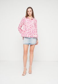 Ροζ μπλούζα με floral σχέδιο, μακριά μανίκια, κουμπιά μπροστά και βολάν στο τελείωμα. Συνδυάζεται με ελαφρύ τζιν μίνι φούστα και λευκά σανδάλια.