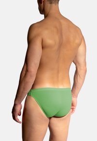 Groene zwembroekjes van ribstof. Het ontwerp heeft een lage taille en een zachte tailleband met minimale bedekking aan de achterzijde.