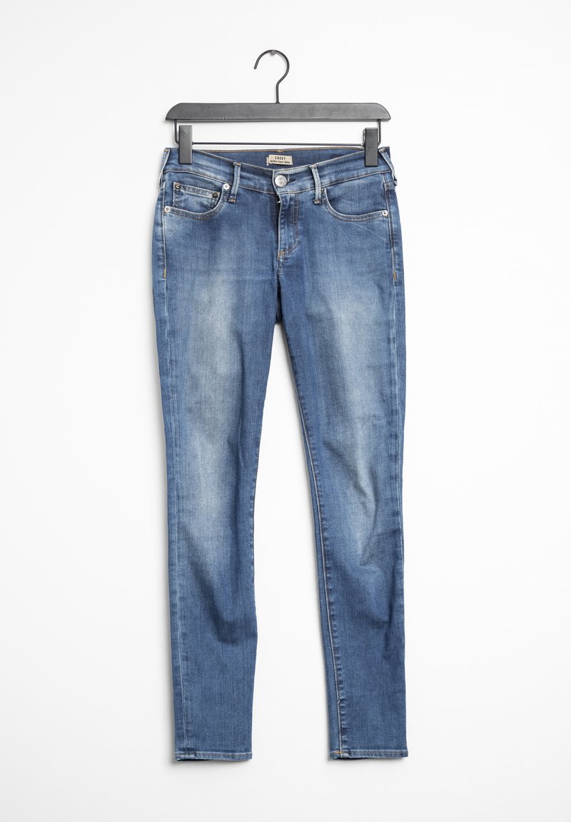 Jean skinny délavé bleu suspendu à un cintre noir sur un fond blanc.