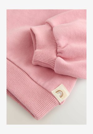 Sweatshirt roz pal cu manșete și tiv cu nervuri. Prezintă un eticheta din material cu un logo curcubeu. Textură moale, design casual.