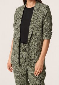 Grüner Leopardenmuster-Blazer mit lockerer Passform, gestaltet mit offenem Vorderteil, Reverskragen und hochgekrempelten Ärmeln. Dazu passende Hose.