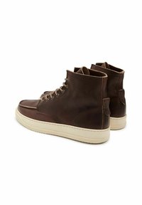 Bottes de cheville en cuir marron avec une finition lisse, semelles en caoutchouc crème, coutures contrastantes et œillets en métal pour les lacets.