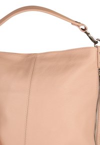 Lichtroze leren handtas met een textuur oppervlak, voorzien van een schouderriem en een ritsdetail aan één kant. Gladde stiknaden als accenten.