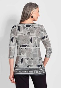 Musterhemd mit langen Ärmeln, das geometrische Formen in Schwarz und Weiß zeigt, mit einem runden Halsausschnitt und Dreiviertelärmeln.