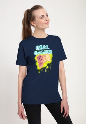 T-shirt en coton bleu marine avec un graphique néon d'une manette de jeu et le texte "REAL GAMER" en jaune et bleu éclatants.