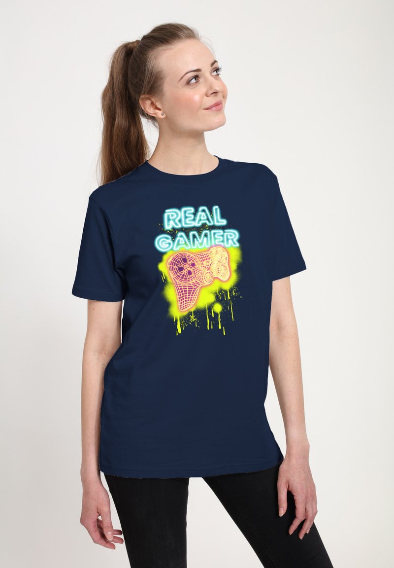 Navy blue cotton t-shirt featuring a neon graphic of a game controller and the text "REAL GAMER" in bright yellow and blue colors.