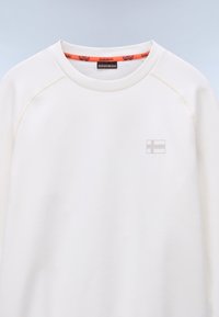Hvit sweatshirt med raglanermer, som har et subtilt Finland-flaggemblem. Den indvendige kragen har oransegule detaljer. Smoother tekstur.