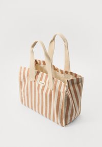 Gestreifte Tragetasche in Beige und Rost, aus Stoff mit zwei stabilen Griffen, mit einem einfachen Logoschild an der Seite.