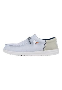 Zapato tipo slip-on de color azul claro con una parte superior de malla texturizada, panel trasero en crema en contraste, cordones grises y suela de goma blanca.