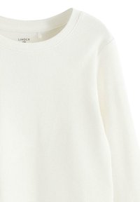 Vitt ribbat långärmad topp med rund halsringning. Har en mjuk textur och minimalistisk design. Etikett visar "Lindex Kids."