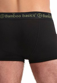 Boxer-briefs en bambou noir avec une large taille verte arborant le logo "Bamboo basics", mettant en avant une texture lisse et un design ajusté.