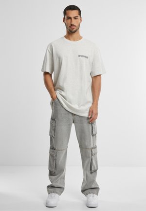 Camiseta de algodón gris claro con un pequeño logo de texto en el pecho, combinada con pantalones cargo gris claro que presentan múltiples bolsillos laterales y puños elásticos.