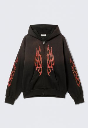 Sweat à capuche noir à fermeture éclair avec une grande poche avant. Présente des motifs de flammes rouges sur la poitrine et les manches. Confectionné en tissu doux avec une coupe décontractée.