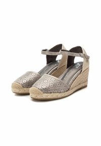 Espadrilles de cuña con una parte superior de un beige metálico, que presentan patrones florales recortados, un tacón envuelto en yute y una delgada correa para el tobillo.