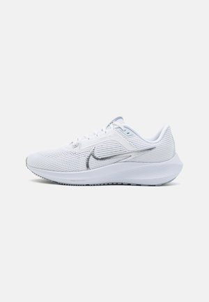 Chaussure de course Nike blanche avec tige en maille respirante, logo swoosh argenté, semelle rembourrée et système de laçage, sur un fond uni.