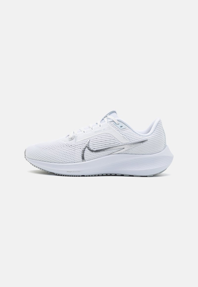 Zapatilla de running blanca de Nike con parte superior de malla transpirable, logotipo Swoosh plateado, suela acolchada y cierre de cordones sobre un fondo sencillo.