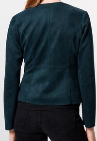 Turkooise suède jas met een aansluitend model, lange mouwen en een soepele, matte textuur. Heeft een naaddetail langs de achterkant.