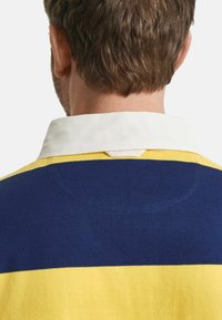 Baumwoll-Polohemd mit gelben und marineblauen Streifen, einem weißen Kragen und einem dreieckigen Akzent am oberen Rückenausschnitt.