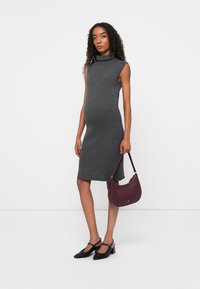 Pilka raštuota midi suknelė su apykakle. Modelis laiko bordo spalvos rankinę ir dėvi juodus smailianosius batus su kulkšnies dirželiais.