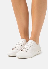 Vita lädersneakers med sex öglor och silverdetaljer, som har en slät yta och subtil branding på sidan.