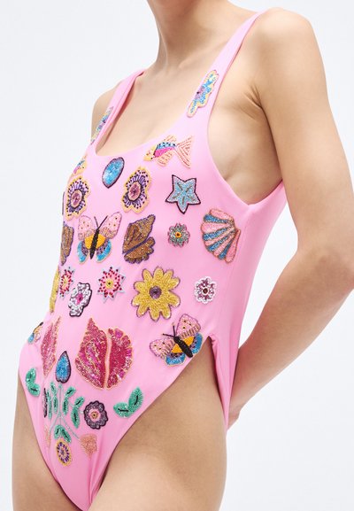 Ružové jednodielne plavky s jemnou viacfarebnou korálkovou výšivkou motýľov, kvetov a mušlí; majú široké ramienka a vysoký strih na nohách.