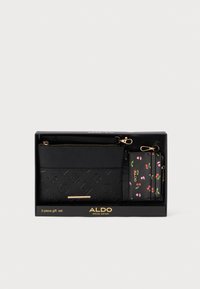 Črn usnjen set denarnic, ki vključuje teksturirano zunanjost s kartico za shranjevanje v cvetličnem vzorcu ter zlatimi dodatki, vse v škatli.