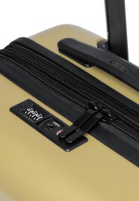Valigia rigida beige con zip nera, doppi cursori della zip e pannello con lucchetto a combinazione. Finitura liscia e testurizzata con un manico resistente.