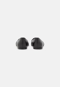 Black leather flats with a rounded toe and minimal stitching. The sole is flat and smooth, providing a sleek, understated design.
