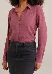 Chemise à manches longues à boutons en rose poussiéreux avec des pois texturés ; associée à une jupe en denim gris foncé taille haute ; col classique et coupe décontractée.