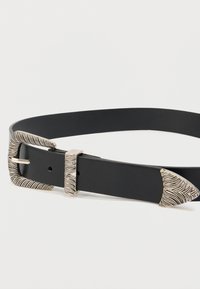 Μαύρη δερμάτινη ζώνη με διακοσμητική αγκράφα σε ασημί απόχρωση, με υφή κυματιστού μοτίβου και μυτερή άκρη. Ρυθμιζόμενη εφαρμογή με ασφαλή κούμπωμα.