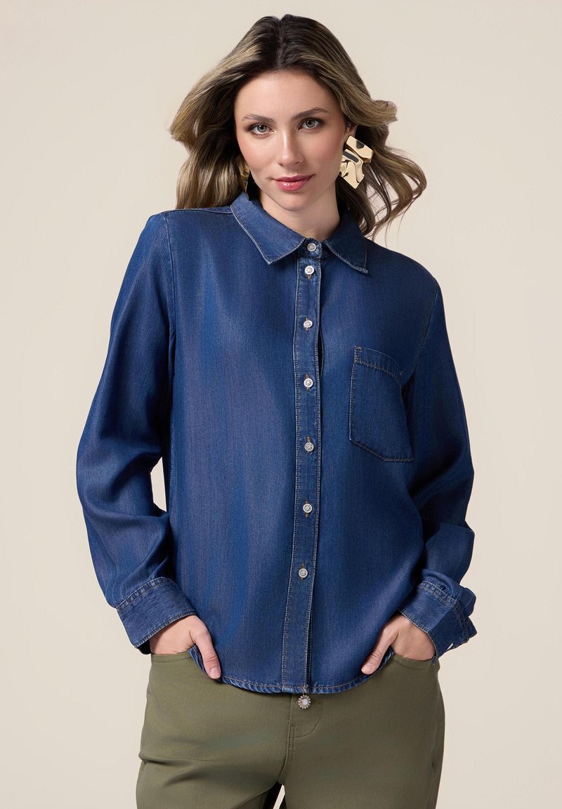 Denim shirt in dark blue, featuring a collared neckline, long sleeves, button closure, chest pocket, and silver button accents.