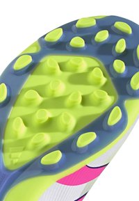 Fodboldstøvle sål med livlige limegrønne studs, en blå accentplade og teksturerede sektioner til greb. Let og strømlinet design.