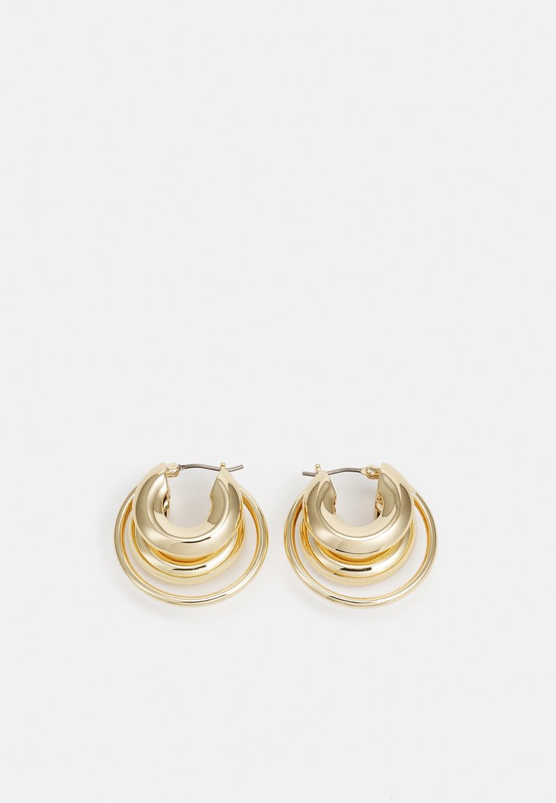 Paire de boucles d’oreilles créoles dorées avec un design circulaire en couches et une finition polie sur fond blanc.