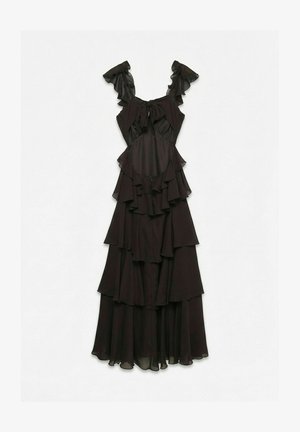 Črna brezrokavna obleka z več plastmi, nagubani trakovi, detajl z mašnico na izrezu in večplastno tekočo tkanino po dolžini.