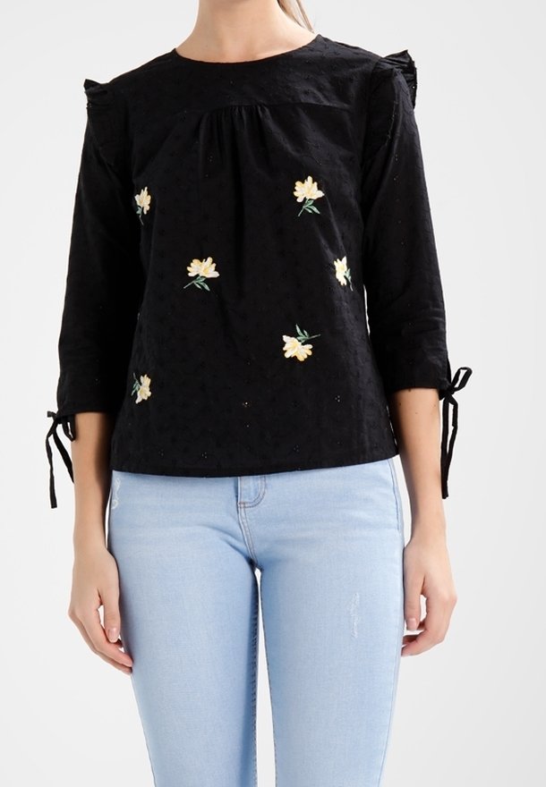 Černá bavlněná blůza se třičtvrtinovými rukávy, zdobená květinovou výšivkou v žluté a zelené. Obsahuje volánkové ramena a mačkané detaily.
