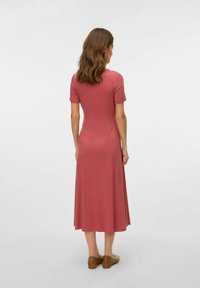Abito midi rosa con maniche corte, corpetto aderente e gonna svasata. Tessuto liscio, abbinato a scarpe marroni slip-on.