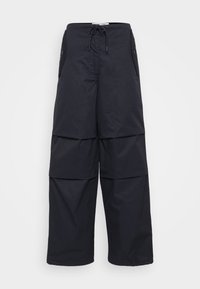 Pantalons courts noirs amples avec taille à cordon, deux poches latérales et panneaux superposés pour plus de texture. Matériau léger.