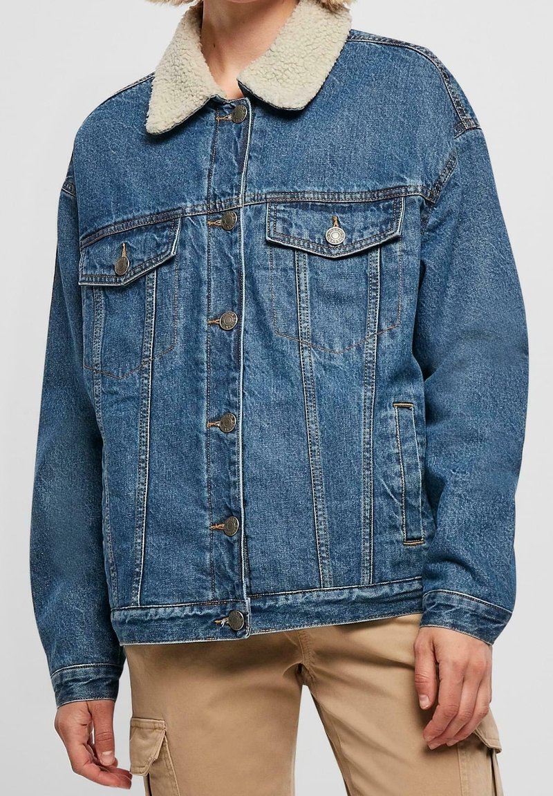 Veste en denim avec un col en shearling doux de couleur crème ; dotée de deux poches poitrine, de boutons à l'avant, et d'une coupe décontractée. Teinture bleue classique.