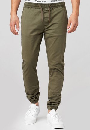 Gröna bomulls-joggingbyxor med elastisk midja, dragsko-stängning och smugna anklar, å paired med vita sneakers.
