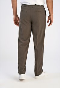 Mörkgrå, lätta byxor med elastisk midja, två bakfickor och smalnande ben, i kombination med vita sneakers.