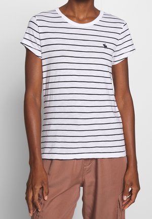 Wit T-shirt met korte mouwen met dunne zwarte horizontale strepen en een klein zwart eland-logo op de linkerborst, gedragen met een bruine broek.