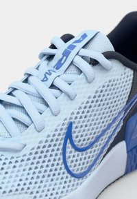 Baskets de sport en mesh bleu clair avec des accents gris foncé. Dotées de lacets plats et d'un célèbre swoosh bleu de Nike sur le côté. Conception respirante.