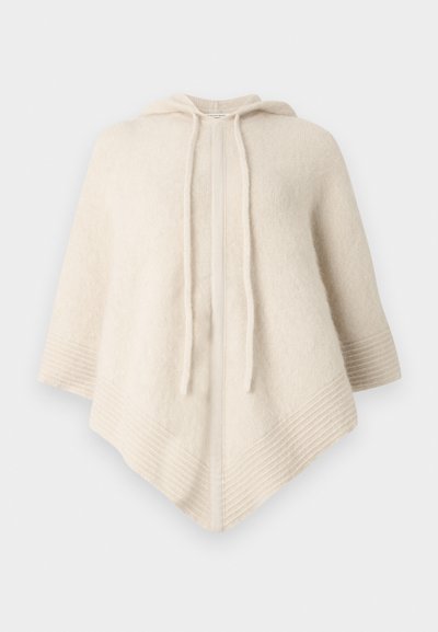 Pončo krem boje s kapuljačom, izrađen od mekanog tkanja. Ima rebraste rubove i prednji otvor sa vezicama.