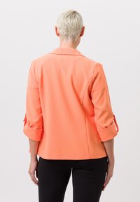Koraalblazer met driekwartmouwen, rol-tabdetail en een ontspannen pasvorm. Gladde stof, met een opstaande kraag en een zoomlijn op heuphoogte.