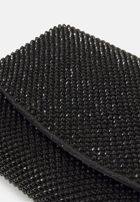 Borsa a tracolla nera con superficie testurizzata decorata con piccole pietre nere sfaccettate, creando un effetto scintillante.