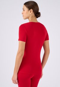 Rode aansluitende top met korte mouwen en een ronde halslijn, gladde textuur en een figuurvormend ontwerp. Geen zichtbare patronen of accenten.