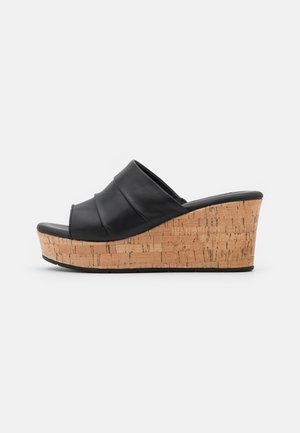 Sort læder kile-sandal med korksål og åben tå, slip-on stil, vist fra siden på hvid baggrund.