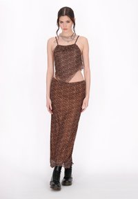 Rochie cu imprimeu de leopard maro, cu bretele subțiri, talie decupată și tiv ondulat. Asortată cu cizme negre cu șireturi. Material neted și transparent.