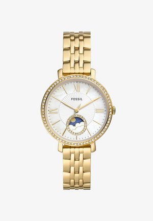 Fossil horloge met een goudkleurige metalen band, ronde witte parelmoeren wijzerplaat, kristallen accenten en een maanfase-indicator aan de onderkant.